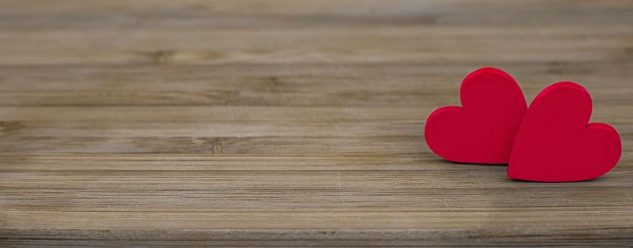 two wooden red hearts on wooden background.