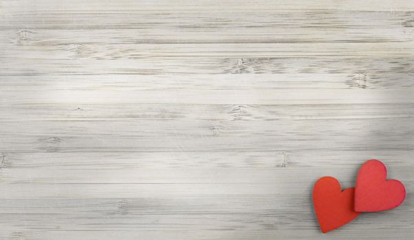 two red wooden hearts in right lower corner of grey wooden background