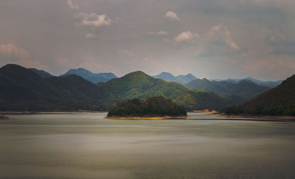 View of lake shore with mountains range in background at sunrise or sunset. Focus and blur.