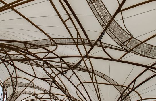 The pattern of steel frame umbrella underside detail with white cloth roof. Selective focus.