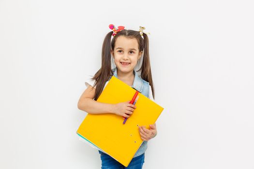 a cute little girl with two tails is holding a folder with papers in her hands. returning to school