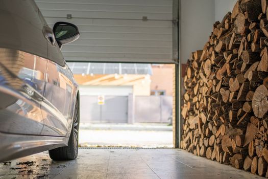 Low angle view of garage with a parked car full of firewood for the winter.