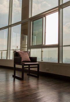 Bangkok, Thailand - Jan 10, 2022 : Brown leather armchair with pillow near the glass window in common area. Working space, Selective focus.