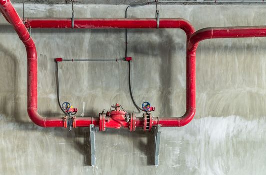 Red water or gas pipeline with gate pressure valve on concrete wall. Industrial tubes and valves, Line pipe industrial and extinguisher pump, Copy space, Selective focus.