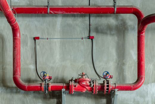 Red water or gas pipeline with gate pressure valve on concrete wall. Industrial tubes and valves, Line pipe industrial and extinguisher pump, Copy space, Selective focus.