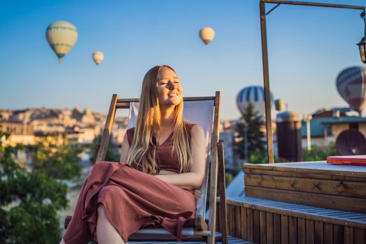 Tourist woman looking at hot air balloons in Cappadocia, Turkey. Happy Travel in Turkey concept. Woman on a mountain top enjoying wonderful view.