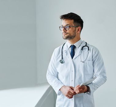 portrait of a young doctor holding a tablet computer in his office in a hospital