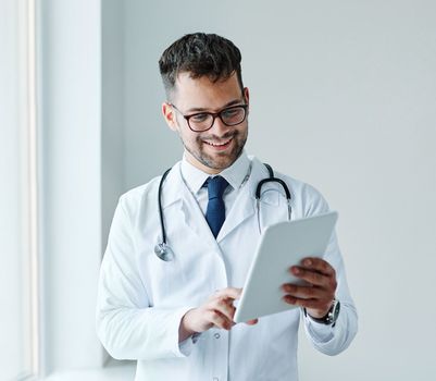 portrait of a young doctor holding a tablet computer in his office in a hospital