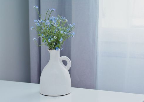 A bouquet of blue forget-me-nots in a white vintage vase Copy space