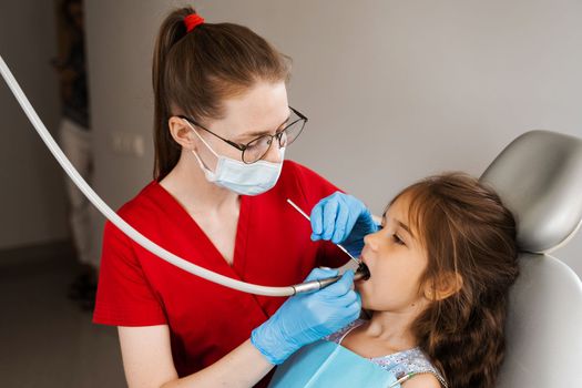 Dental drill. Child dentist drilling teeth of kid girl in dentistry clinic. Dental filling for child patient