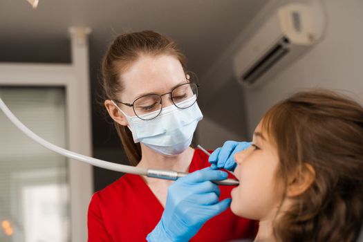 Dental drill. Child dentist drilling teeth of kid girl in dentistry clinic. Dental filling for child patient