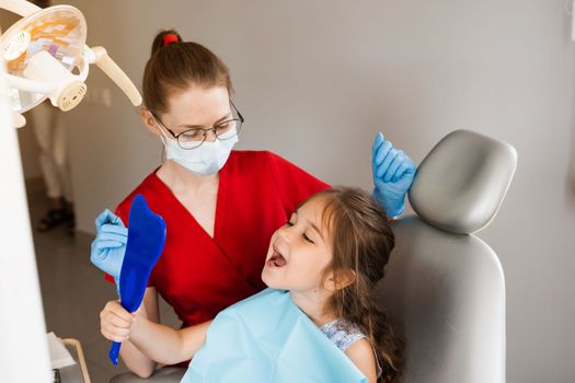 Children dentistry. Dentist and child patient. Consultation with child dentist at dentistry. Teeth treatment. Child looking in the mirror at the dentist. Happy child patient of dentistry