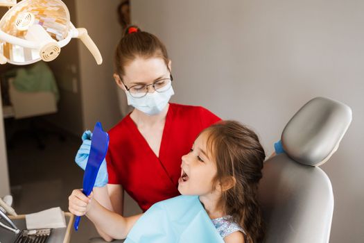 Children dentistry. Dentist and child patient. Consultation with child dentist at dentistry. Teeth treatment. Child looking in the mirror at the dentist. Happy child patient of dentistry