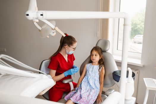 Child girl afraid dentist. Childrens dentist consults frightened kid in dentistry. Treatment of teeth and toothache in children