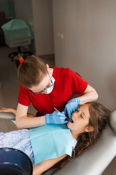 Consultation with child dentist at dentistry. Teeth treatment. Children dentist examines girl mouth and teeth and treats toothaches. Happy child patient of dentistry