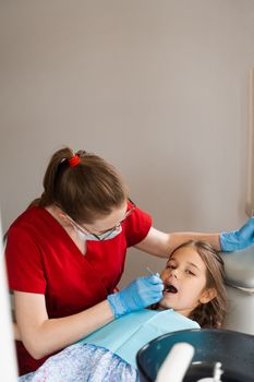 Consultation with child dentist at dentistry. Teeth treatment. Children dentist examines girl mouth and teeth and treats toothaches. Happy child patient of dentistry