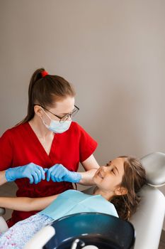 Consultation with child dentist at dentistry. Teeth treatment. Children dentist examines girl mouth and teeth and treats toothaches. Happy child patient of dentistry
