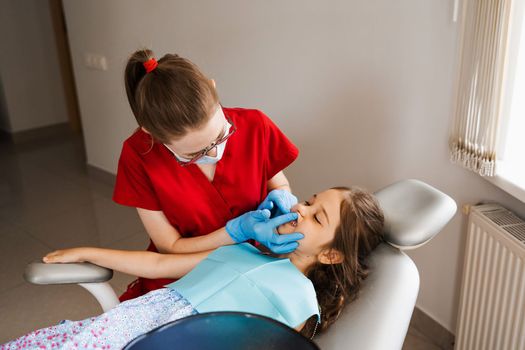 Consultation with pediatric dentist in dentistry. Pediatric dentist examines teeth of child girl for treatment of toothache. Pain in teeth in children