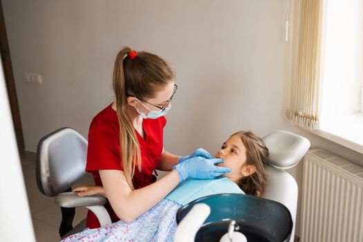 Consultation with pediatric dentist in dentistry. Pediatric dentist examines teeth of child girl for treatment of toothache. Pain in teeth in children