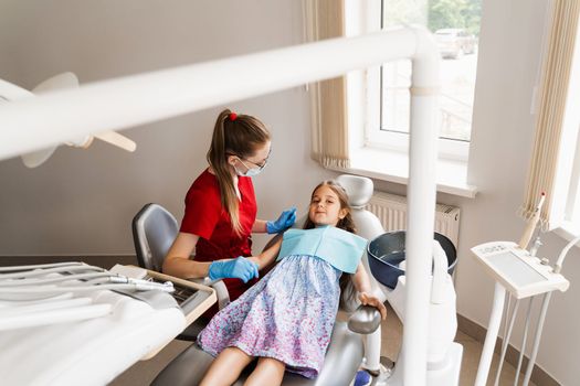 Pediatric dentist and cheerful girl child smiling in dentistry. The child smiles at the consultation with the dentist