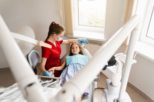 Pediatric dentist and cheerful girl child smiling in dentistry. The child smiles at the consultation with the dentist