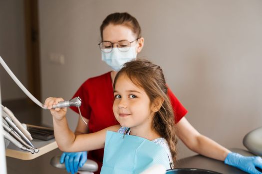 Cheerful girl child holding stomatology tools and smile in dentistry. The child smiles at the consultation with the dentist