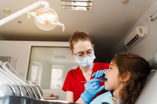 Consultation with pediatric dentist at dentistry. Teeth treatment. Children dentist examines girl mouth and teeth and treats toothaches. Happy child patient of dentistry