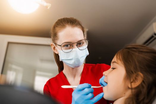 Consultation with pediatric dentist at dentistry. Teeth treatment. Children dentist examines girl mouth and teeth and treats toothaches. Happy child patient of dentistry