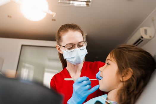 Consultation with pediatric dentist at dentistry. Teeth treatment. Children dentist examines girl mouth and teeth and treats toothaches. Happy child patient of dentistry