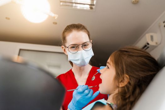 Pediatric dentist and cheerful girl child smiling in dentistry. The child smiles at the consultation with the dentist