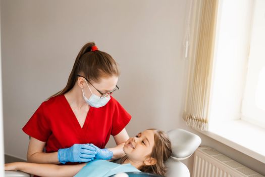 Consultation with child dentist at dentistry. Teeth treatment. Children dentist examines girl mouth and teeth and treats toothaches. Happy child patient of dentistry