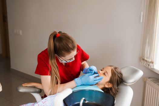 Consultation with pediatric dentist in dentistry. Pediatric dentist examines teeth of child girl for treatment of toothache. Pain in teeth in children