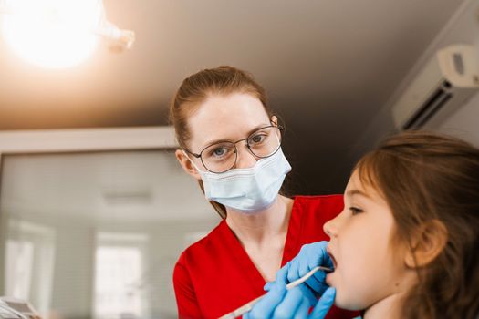 Consultation with pediatric dentist at dentistry. Teeth treatment. Children dentist examines girl mouth and teeth and treats toothaches. Happy child patient of dentistry