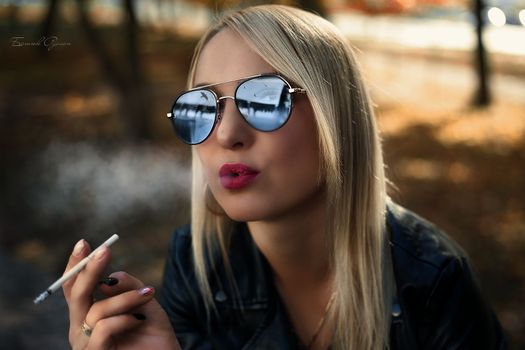 Fashion art portrait of beauty model woman in bright lights with colorful smoke. Smoking girl, Close up of a female inhaling from an electronic cigarette. High quality photo