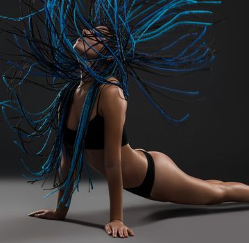 Brunette with blue dreadlocks wearing black lingerie against black wall