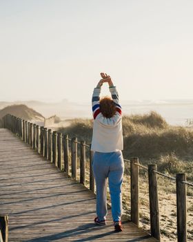 Mature woman exercise in morning, Adult female stretching muscle against beach dunes, warm up. Active lifestyle concept.