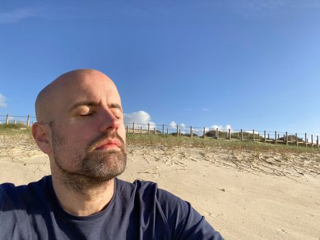 Man taking a moment to relax and meditate raising his face to the sun