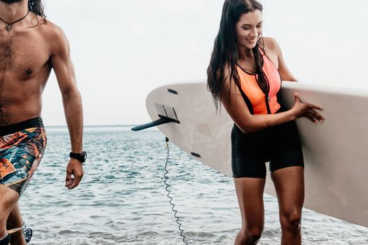 Sea woman and man on sup. Silhouette of happy young woman and man, surfing on SUP board, confident paddling through water surface. Idyllic sunset. Active lifestyle at sea or river