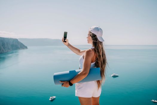 Young woman with black hair, fitness instructor in pink sports leggings and tops, doing pilates on yoga mat with magic pilates ring by the sea on the beach. Female fitness daily yoga concept