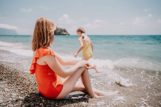 Happy loving family mother and daughter having fun together on the beach. Mum playing with her kid in holiday vacation next to the ocean - Family lifestyle and love concept.