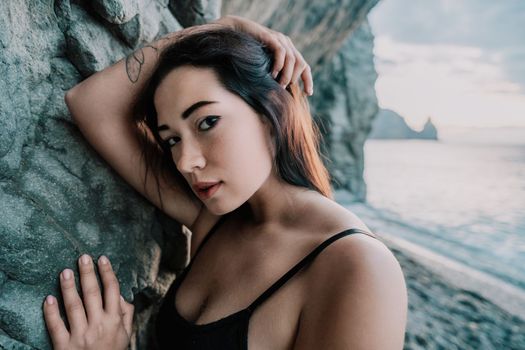 Portrait of cheerful female climber ascending a rock. The athlete girl trains in nature. Woman overcomes difficult climbing route.