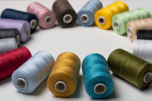 spools of colored sewing thread on white background with copy space