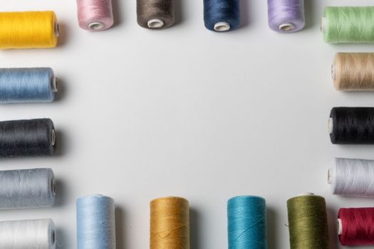 spools of colored sewing thread on white background with copy space