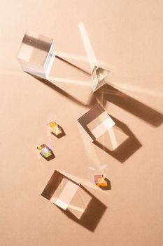 Glass prisms reflect light making beautiful shadows on beige background, glass podiums for beauty products