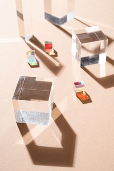 Glass prisms reflect light making beautiful shadows on beige background, glass podiums for beauty products