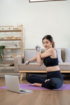 sport, fitness and healthy lifestyle concept - happy smiling young asian woman with laptop computer stretching arm at home.