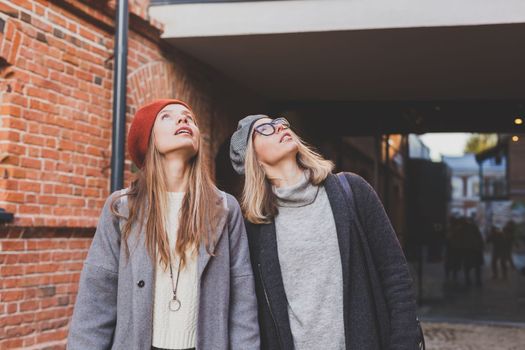 Young pretty girls friends having fun outdoor in autumn evening in city laughing and going crazy on the street - friendship and funny people