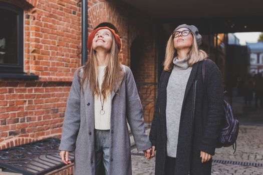 Young pretty girls friends having fun outdoor in autumn evening in city laughing and going crazy on the street - friendship and funny people