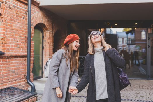 Young pretty girls friends having fun outdoor in autumn evening in city laughing and going crazy on the street - friendship and funny people