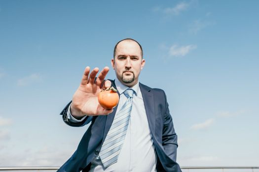Male persimmon park. Hipster millennial man in a tie and jacket bites off a persimmon while sitting on a park bench in slow motion Young business people eat golden persimmons at lunchtime